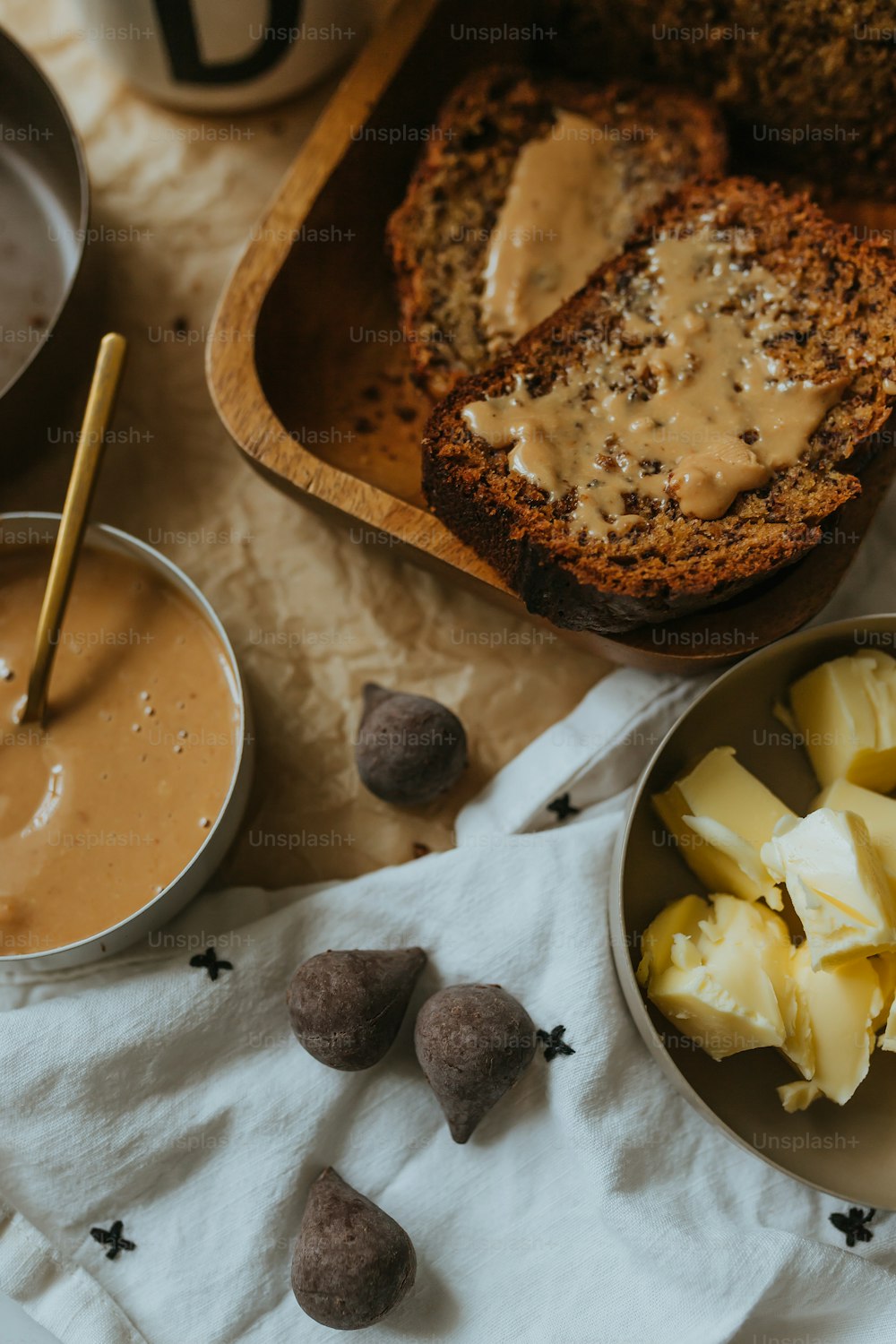 a bowl of fruit, a loaf of bread, and some nuts on a table