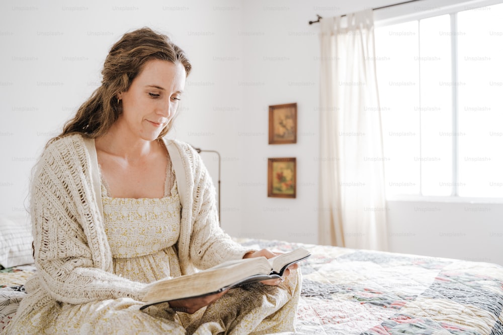 a woman sitting on a bed reading a book