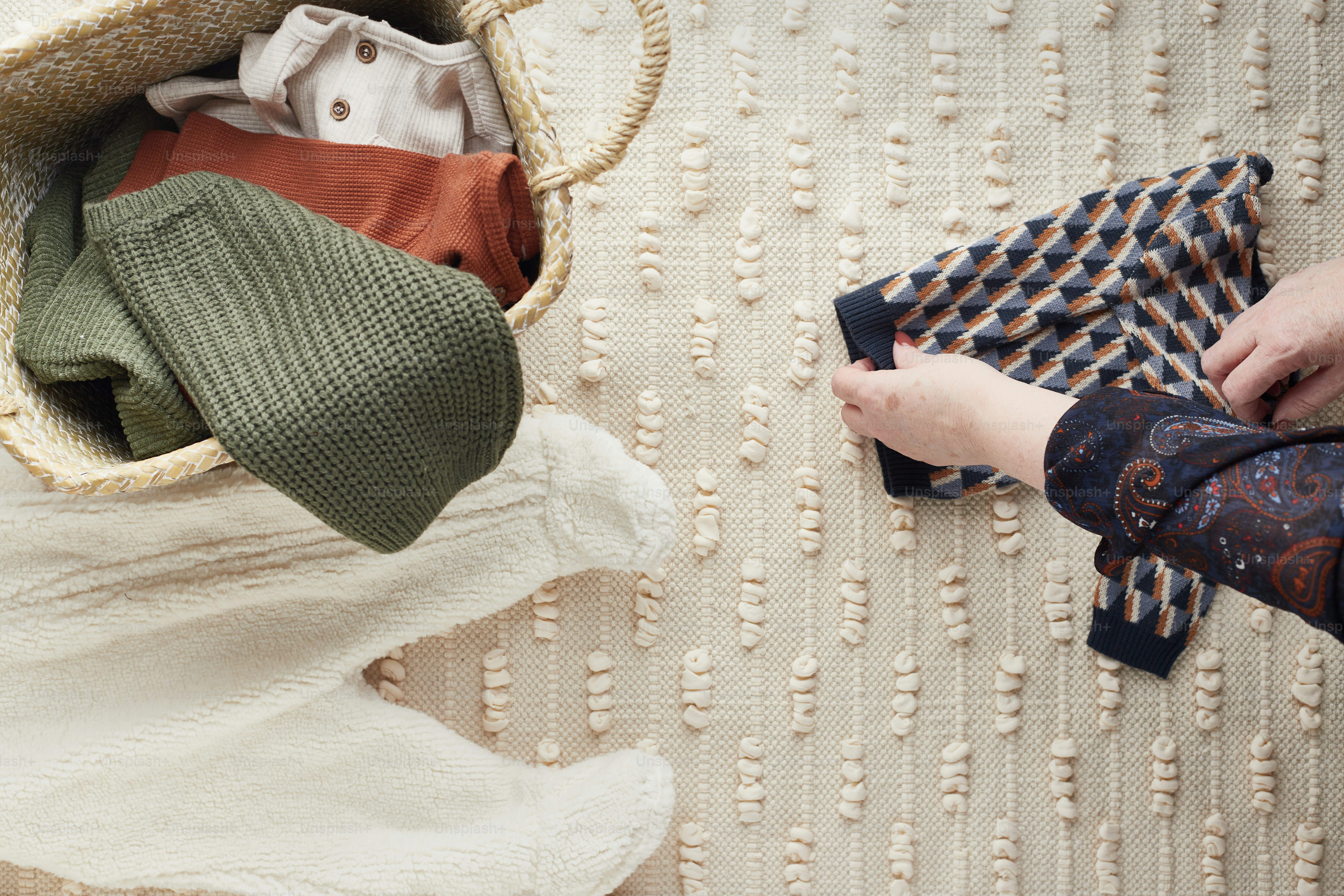 a person holding a piece of cloth next to a basket filled with clothes
