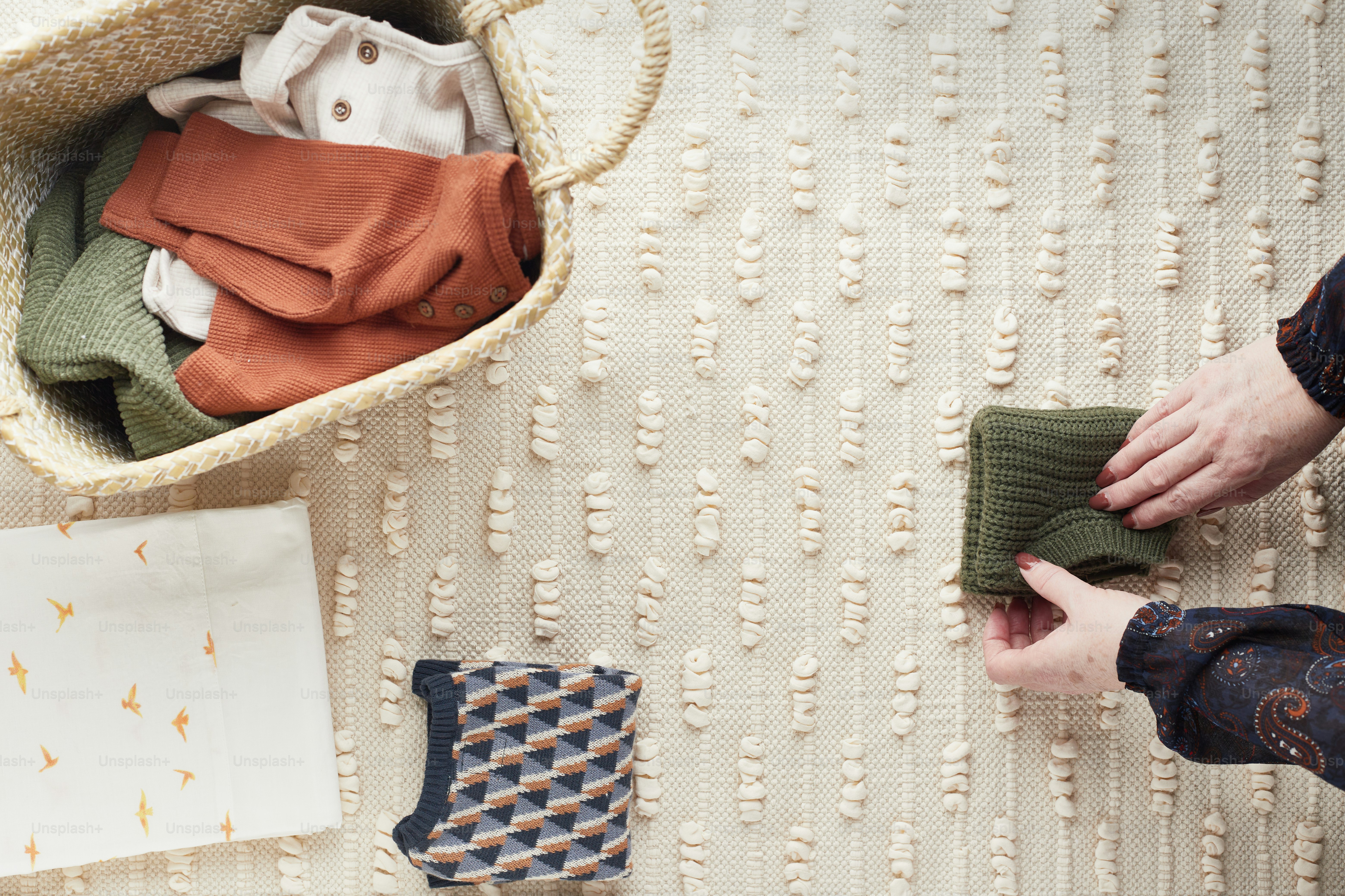 a person holding a pair of socks next to a basket of folded clothes