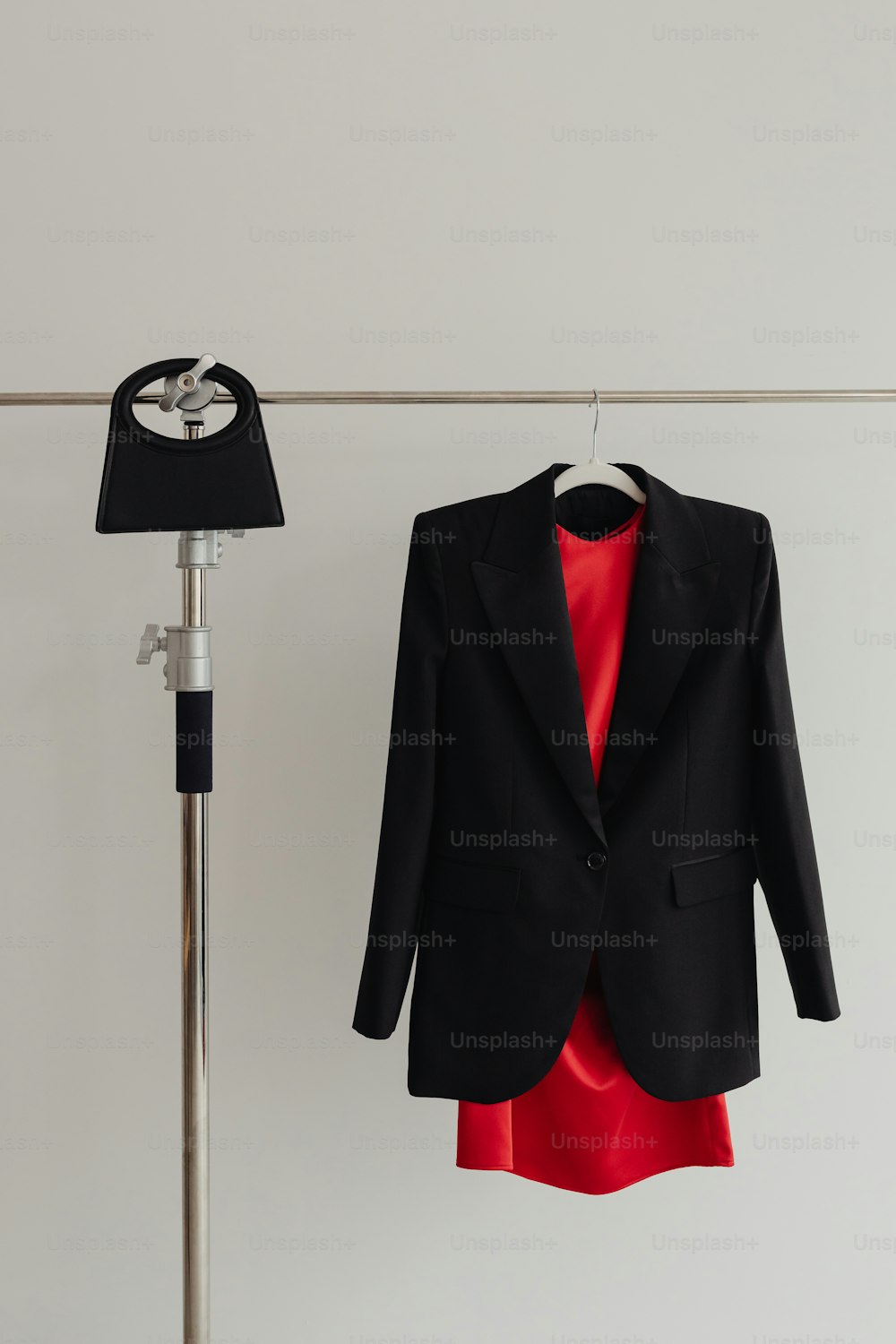 Una giacca nera appesa a una linea di vestiti accanto a un vestito rosso