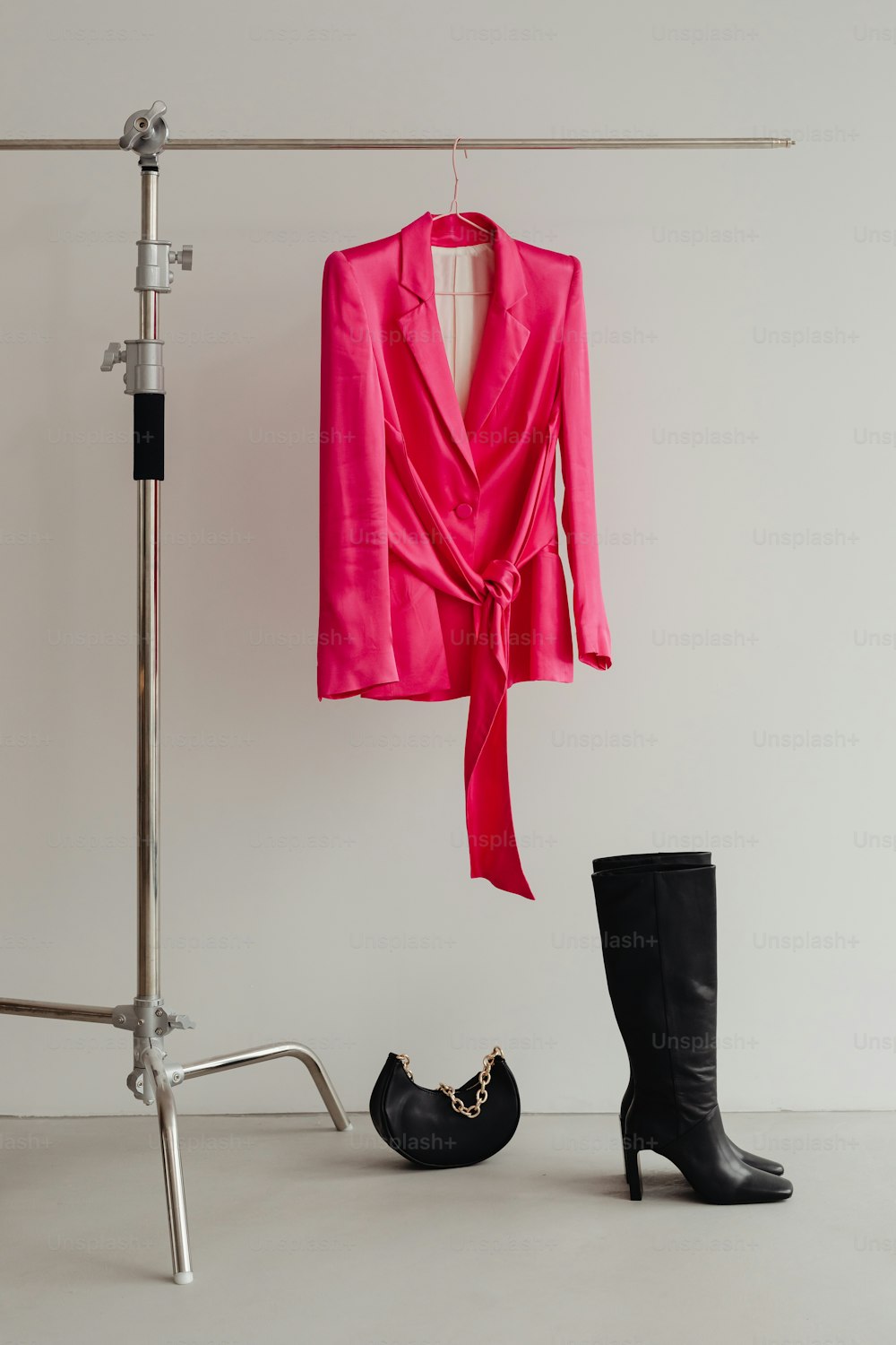 검은 부츠 한 켤레와 옷걸이에 걸려 있는 분홍색 재킷
