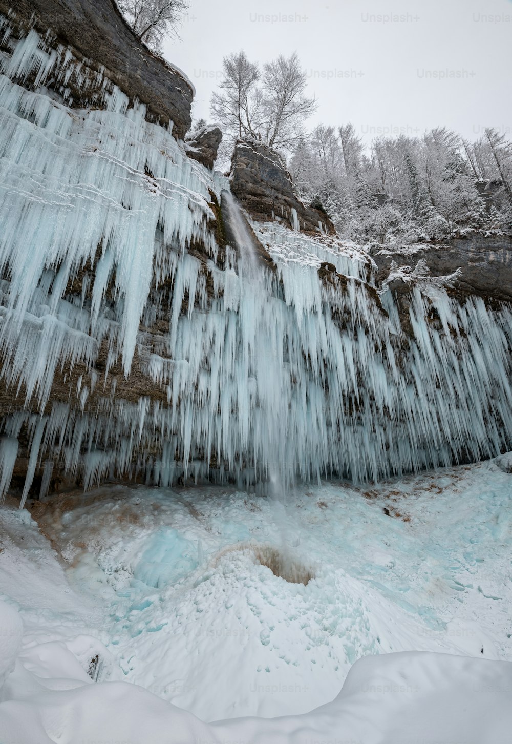 a large waterfall covered in ice next to a forest