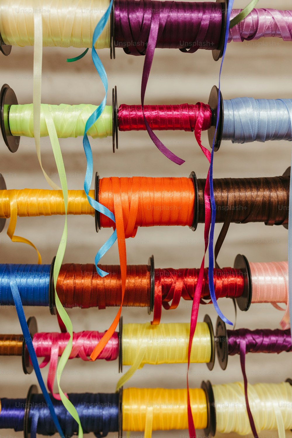 a bunch of spools of thread hanging on a wall