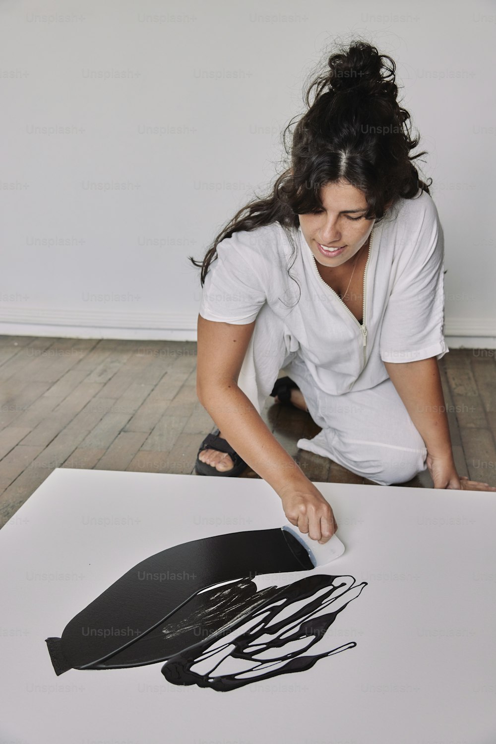 a woman sitting on the floor working on a piece of art