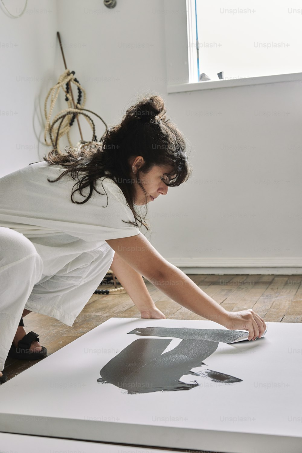 uma mulher em um vestido branco está pintando uma imagem