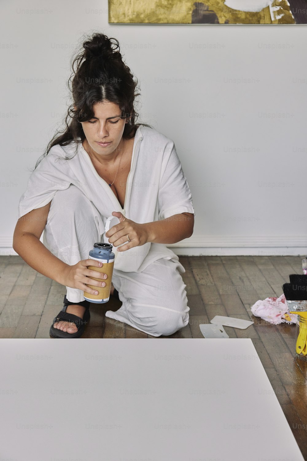 Eine Frau sitzt mit einer Dose Kaffee auf dem Boden