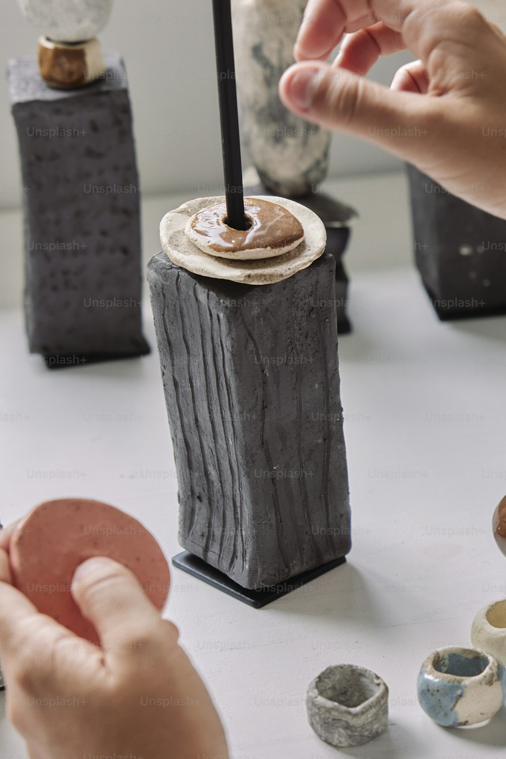 Eine Person dekoriert eine Vase mit Ton