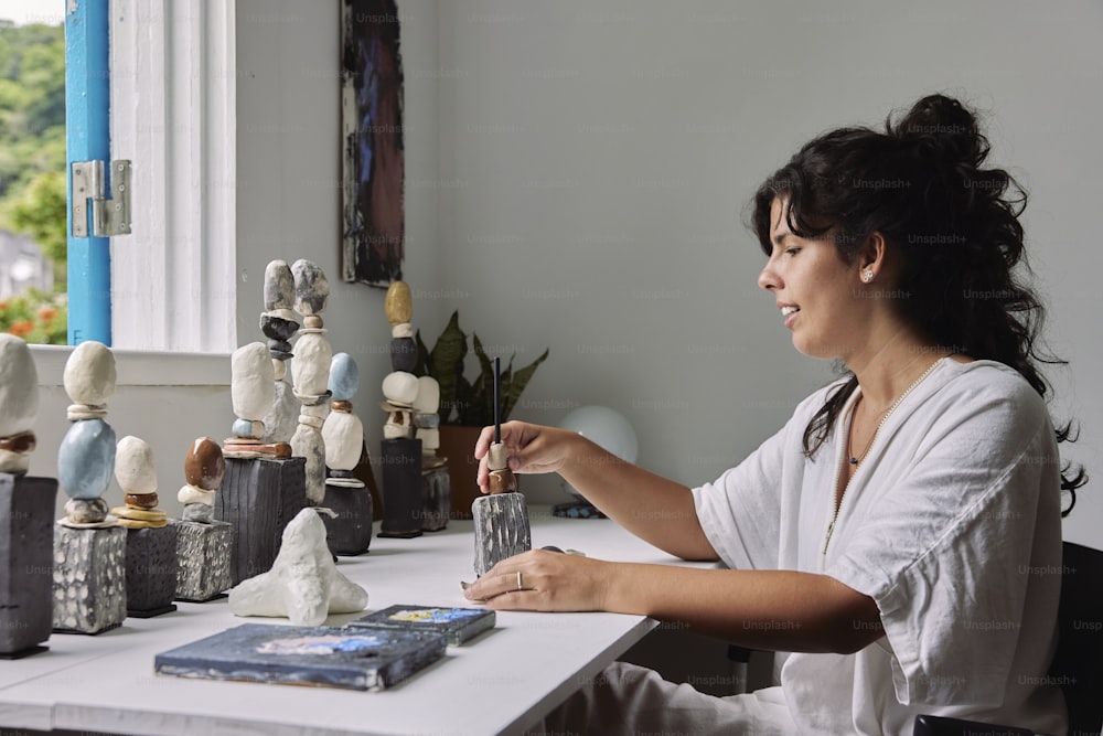 a woman sitting at a table with a book and some figurines