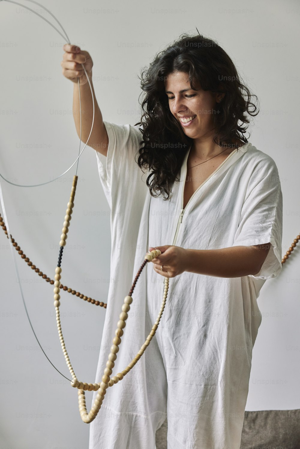 a woman in a white dress holding a string of beads