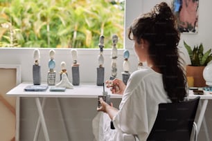 a woman sitting in a chair looking at a display of figurines