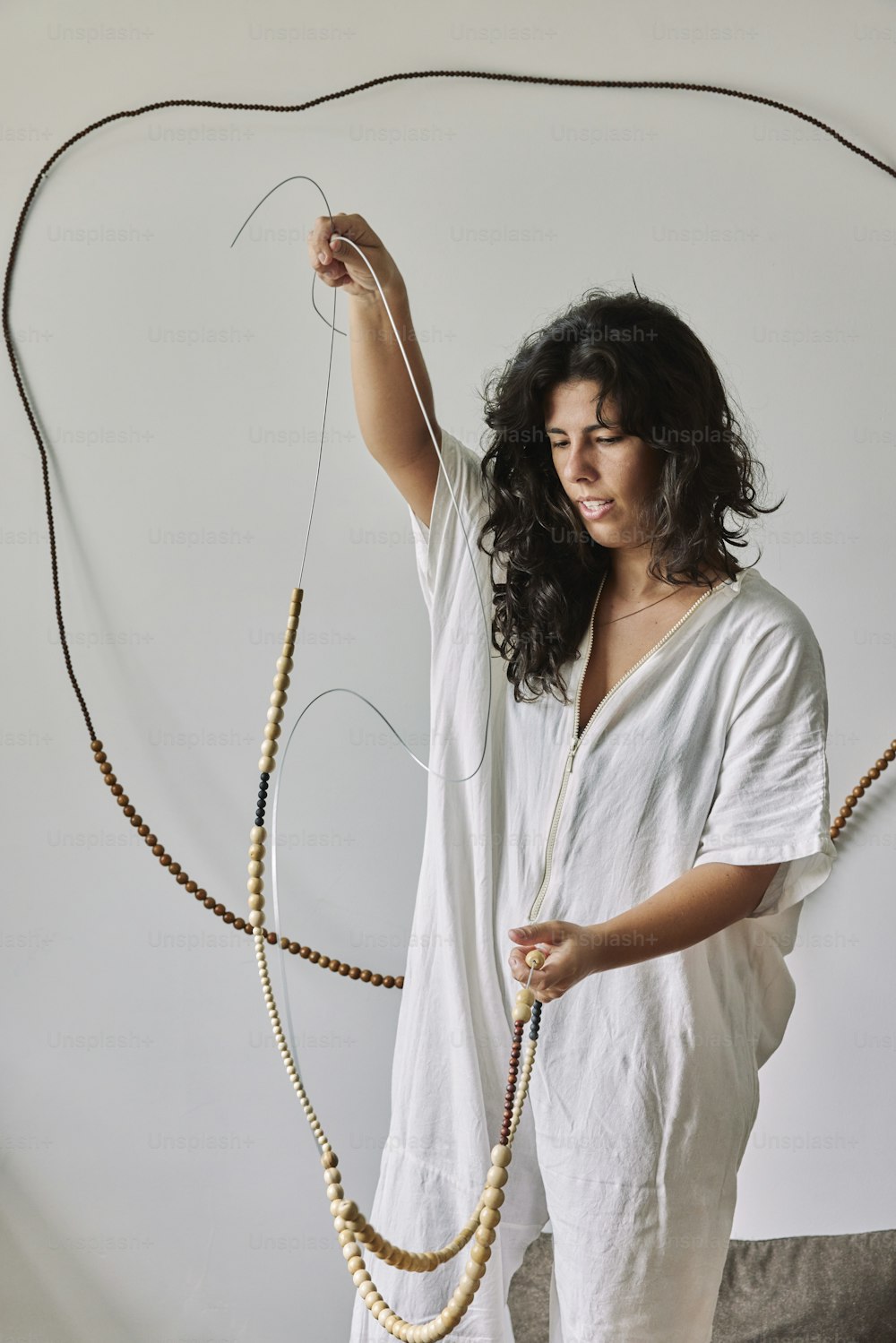 a woman holding a string and a string of beads