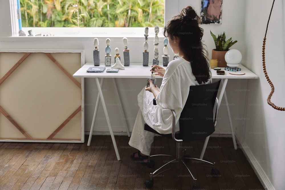 a woman sitting at a desk in front of a window