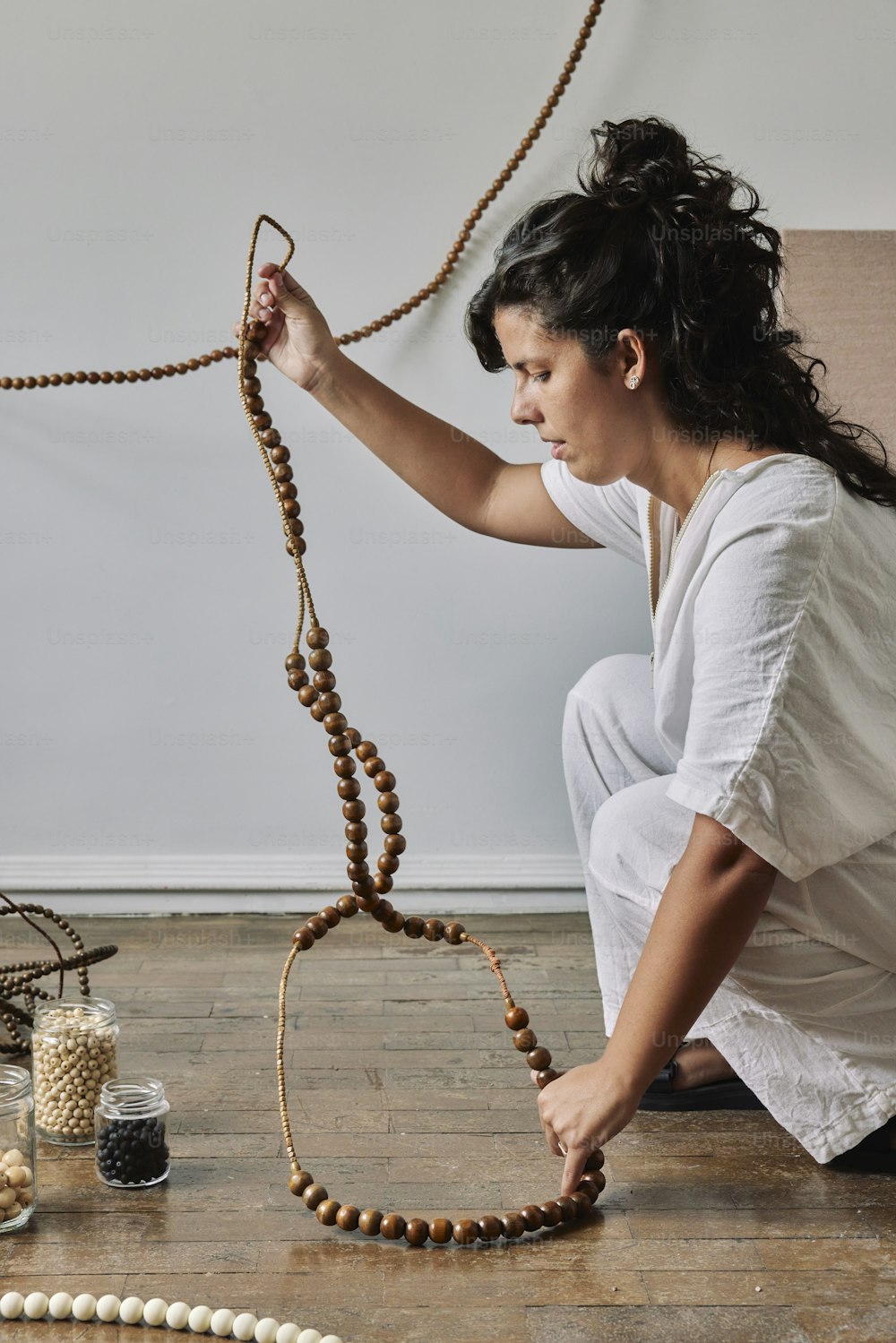 a woman kneeling on the floor holding a string of beads