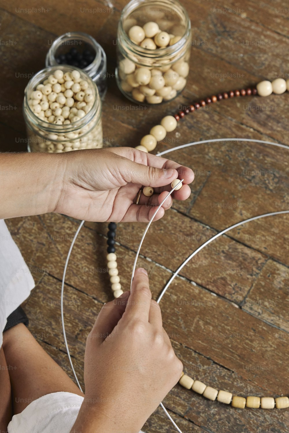 une personne fabrique un collier de perles avec des perles de bois