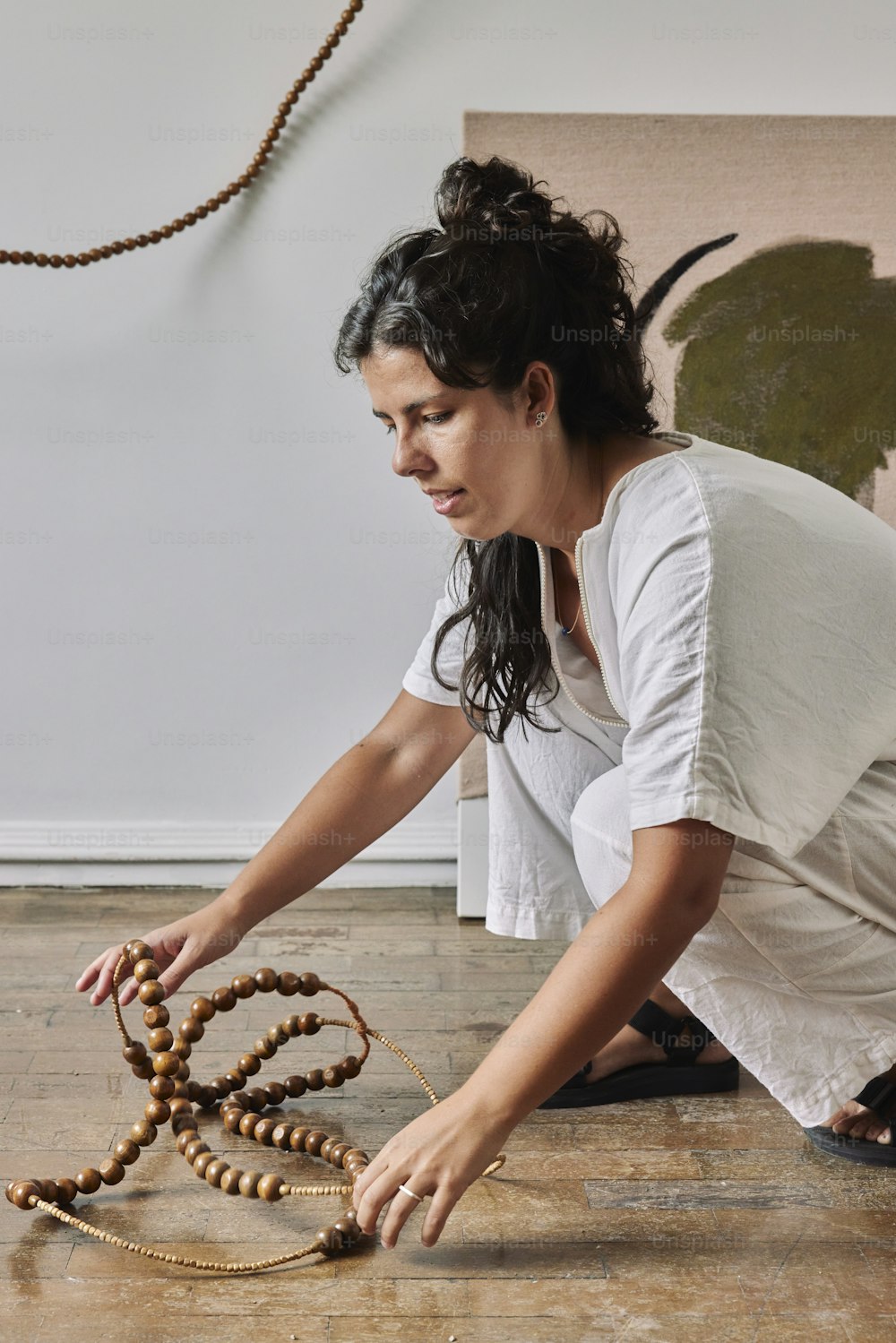 a woman kneeling down on the floor with a beaded necklace