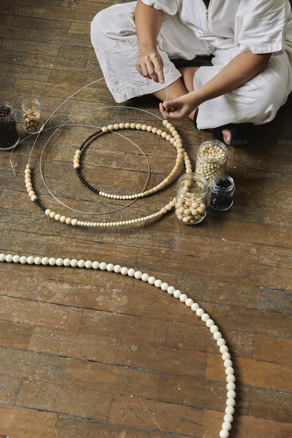 a woman sitting on the floor next to a string of beads