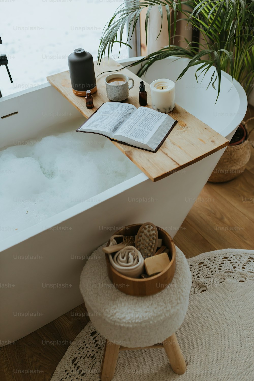 a bathtub with a book, candles, and a candle holder