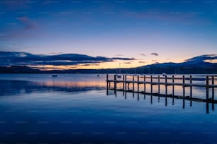 a dock on a lake at sunset with mountains in the background