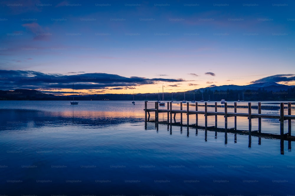 a dock on a lake at sunset with mountains in the background