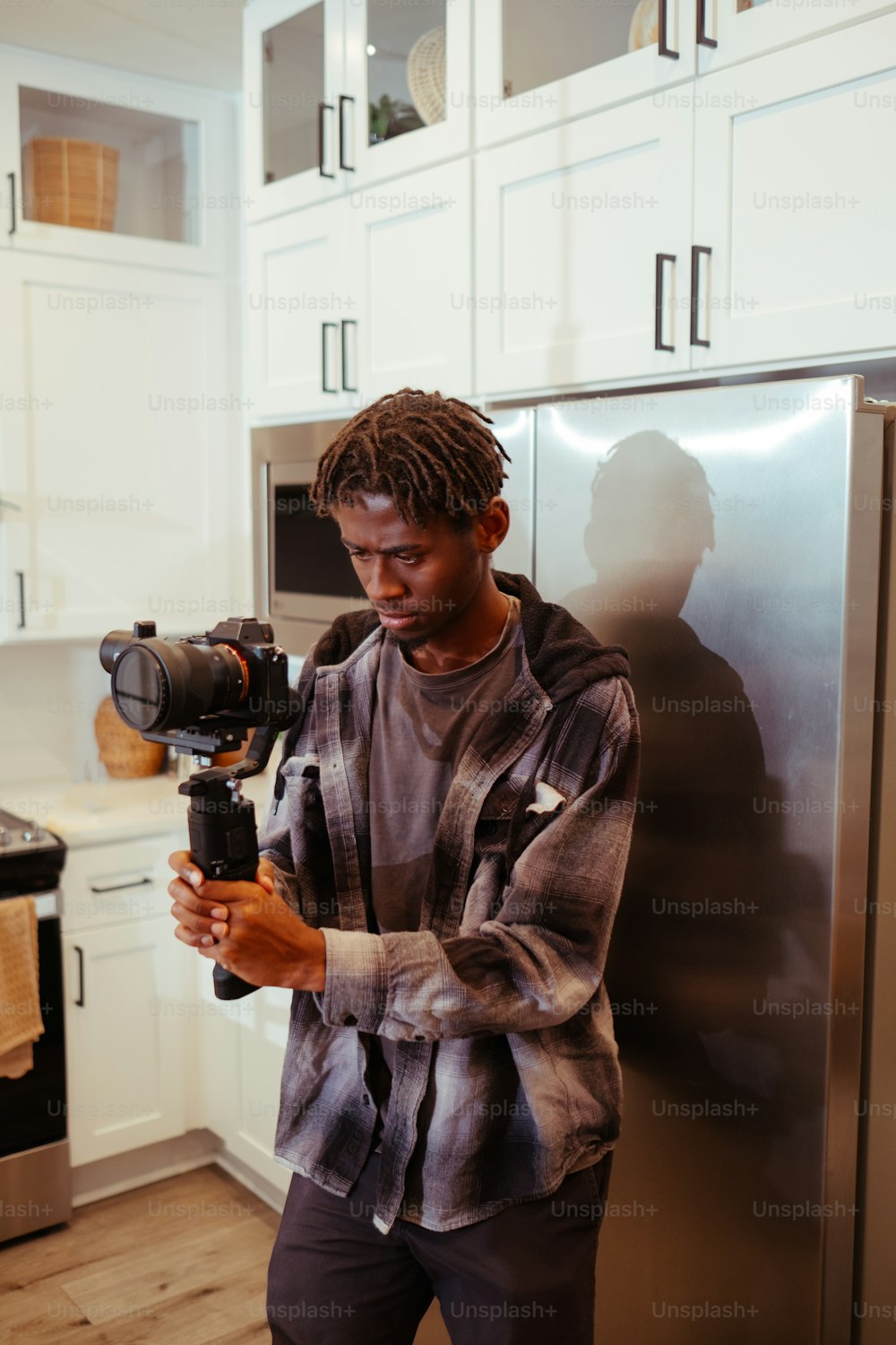 Un hombre sosteniendo una cámara en una cocina