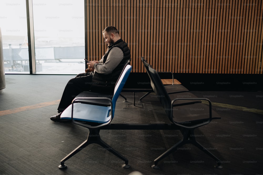 a man sitting in a chair looking at his cell phone