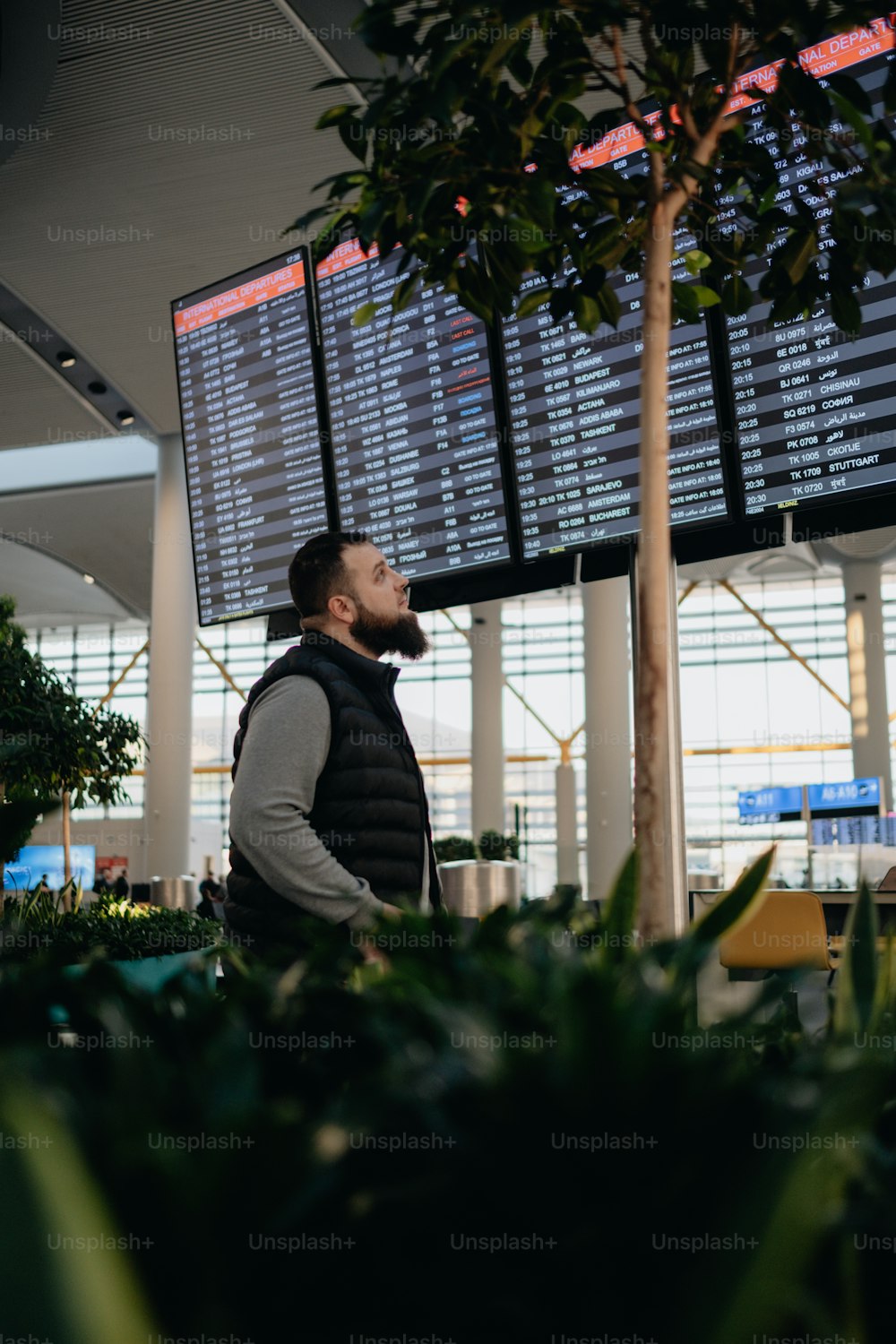 um homem em pé na frente de uma tela grande em um aeroporto