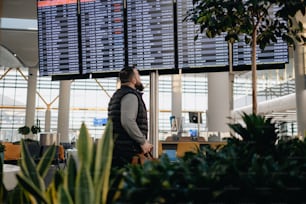 Un uomo in piedi davanti a un grande schermo in un aeroporto