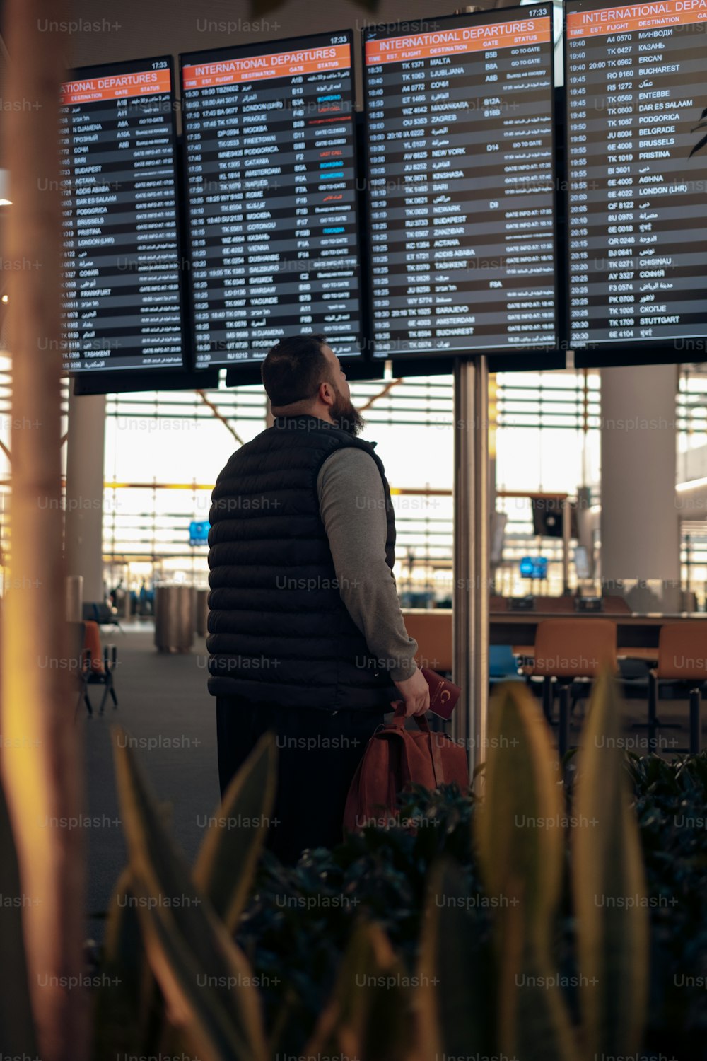 Ein Mann steht vor einer großen Leinwand an einem Flughafen