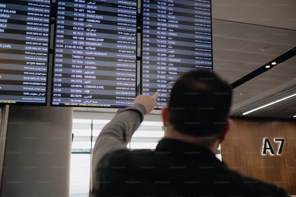 a man pointing at a large screen with numbers on it