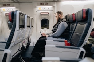 飛行機に座って携帯電話を見ている男性