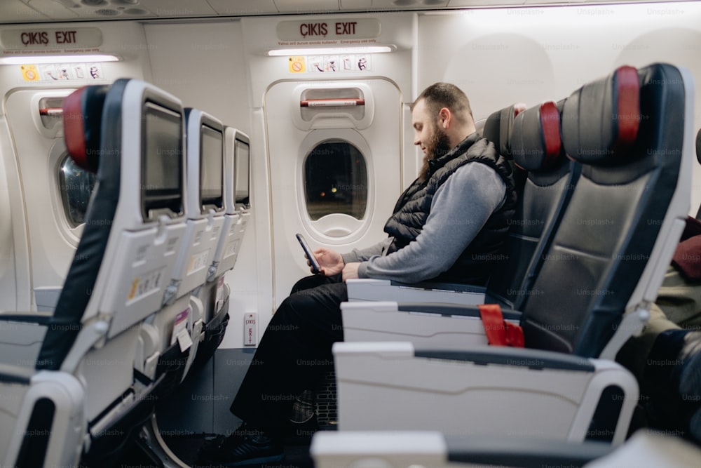 Ein Mann sitzt in einem Flugzeug und schaut auf sein Handy