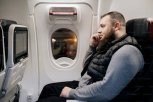 Un hombre sentado en un avión mirando por la ventana
