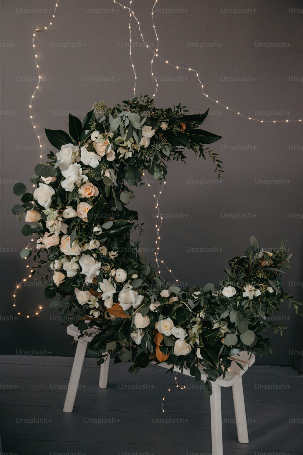 a wreath with white flowers and greenery on it