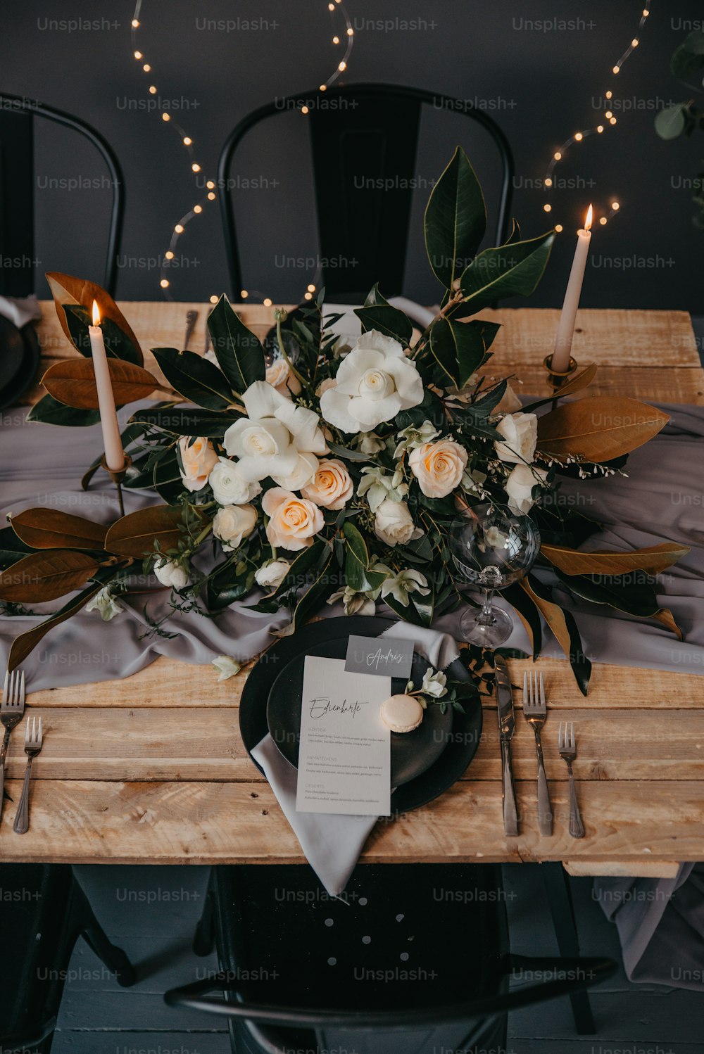 a wooden table topped with a black plate and a bouquet of flowers