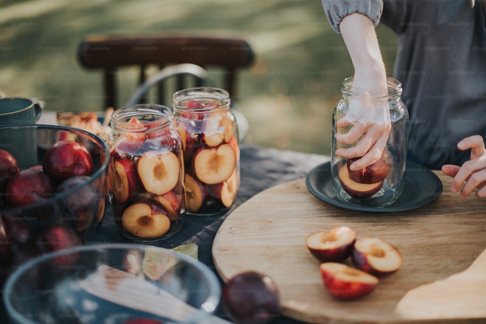 a person putting apples in a jar on a table