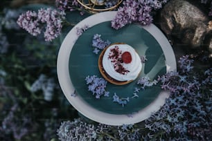 a small dessert on a plate surrounded by purple flowers