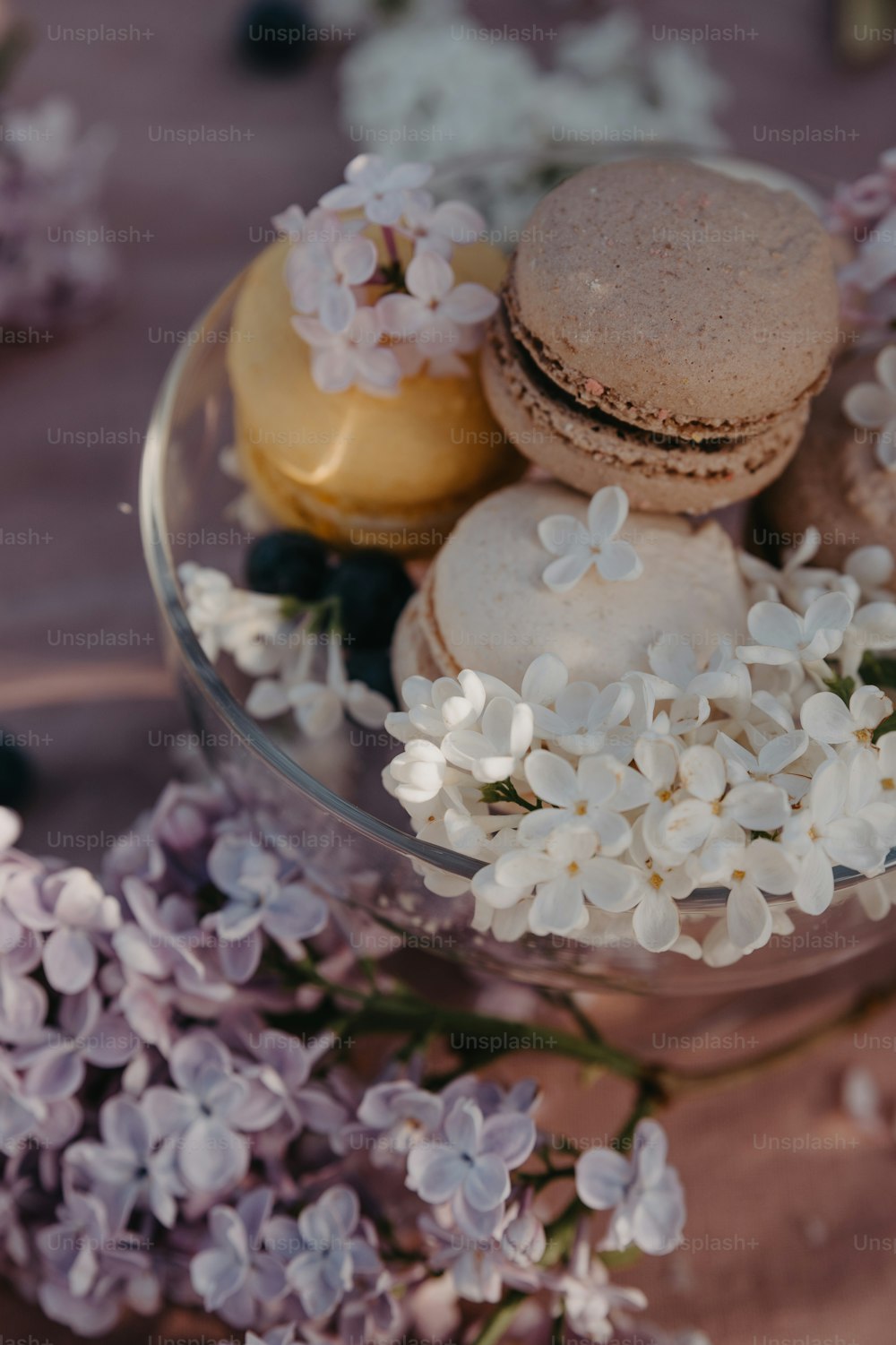 uma tigela de vidro cheia de macarons e flores