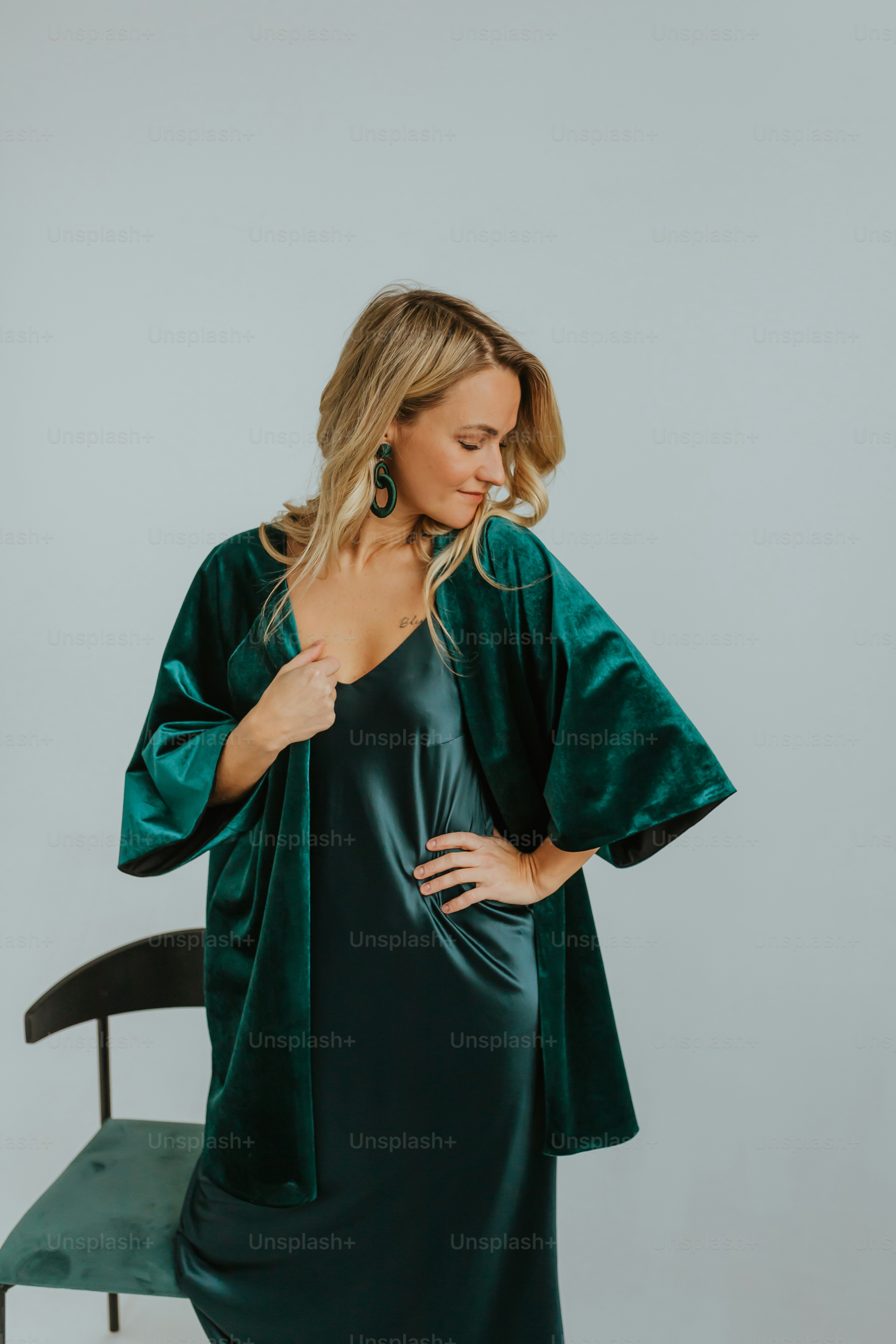 a woman in a green dress standing next to a chair