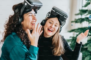 two women wearing virtual headsets in front of a christmas tree