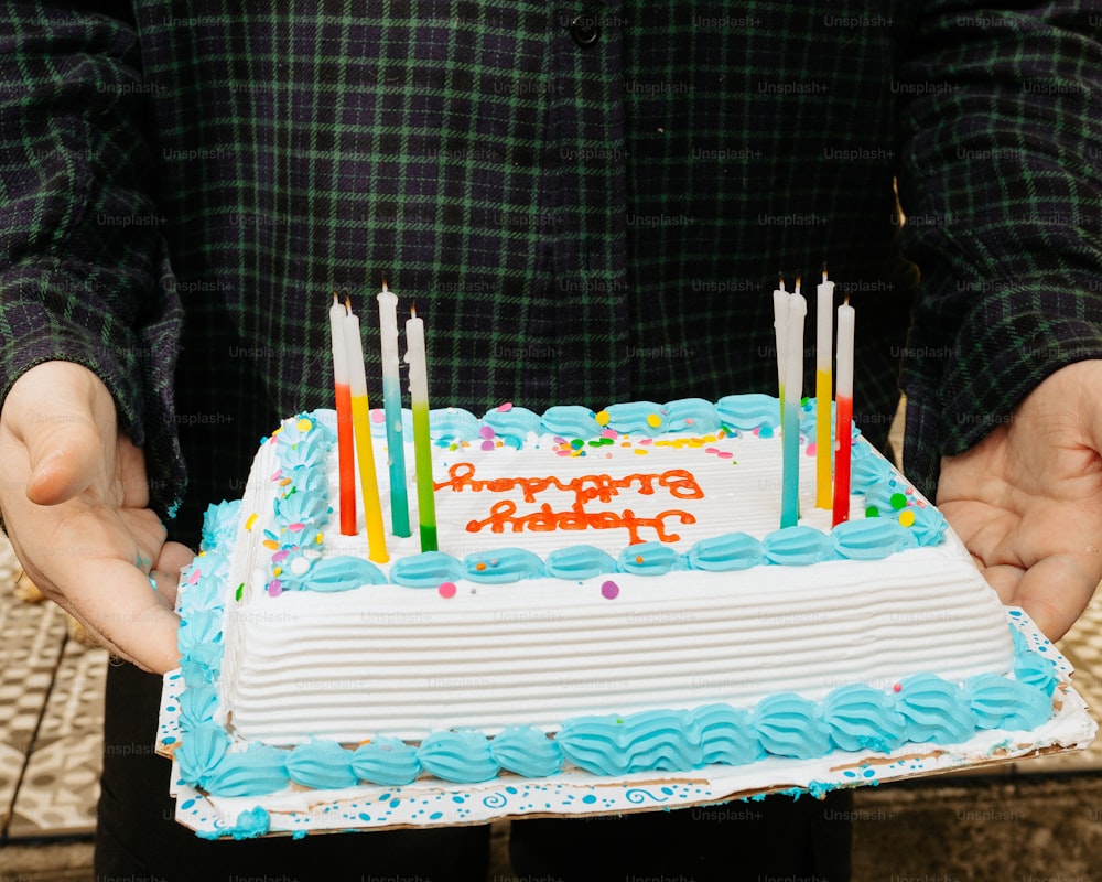 una persona che tiene una torta di compleanno con le candele