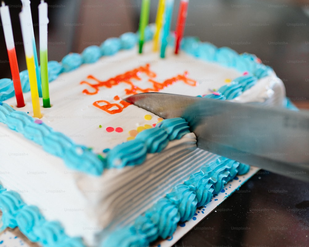 a person cutting a birthday cake with a knife