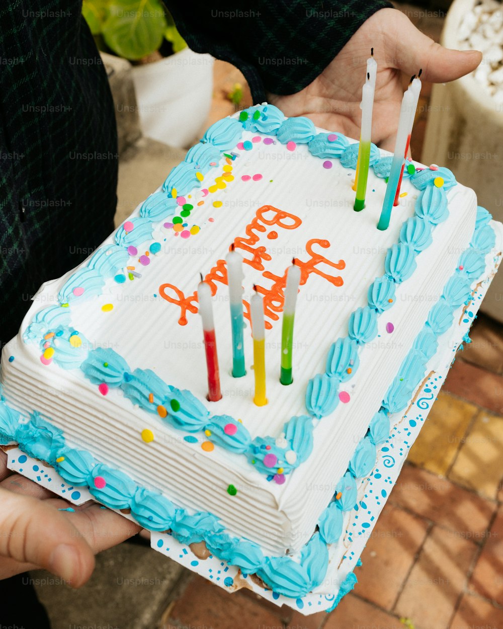 a person holding a birthday cake with candles
