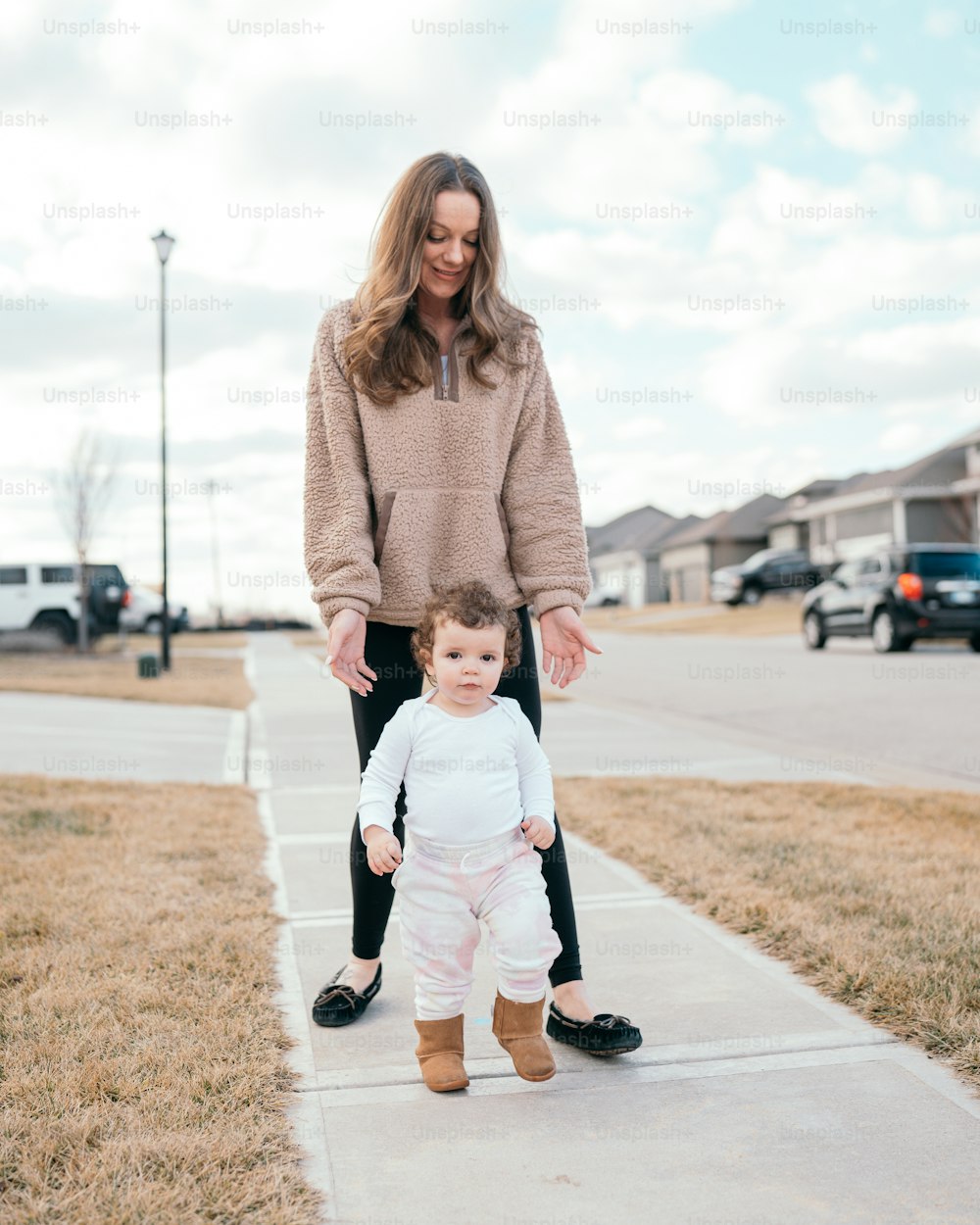 a woman and a baby standing on a sidewalk