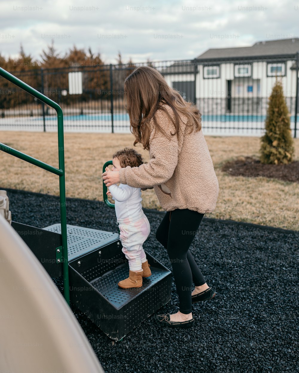 a woman holding a baby up to a slide