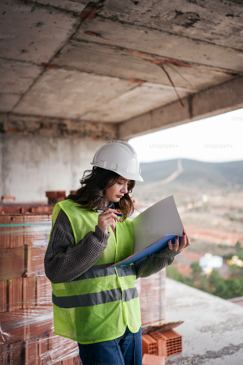 a woman in a hard hat and safety vest holding a clipboard