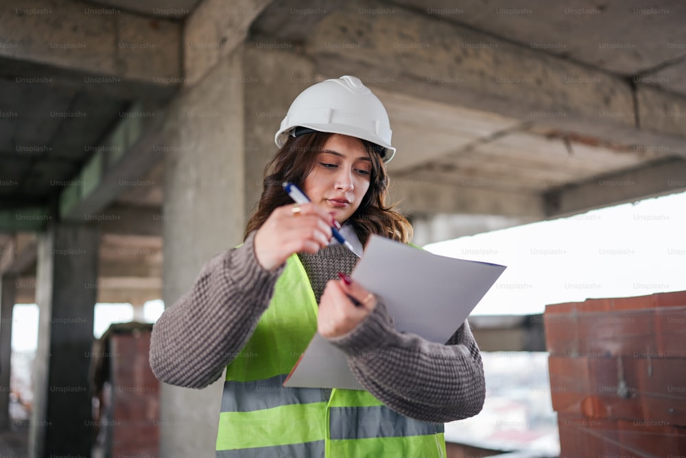 a woman in a hard hat and safety vest writing on a piece of paper