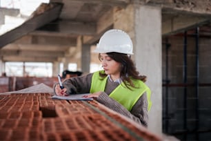 a woman in a hard hat is writing on a piece of paper