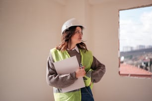 a woman wearing a hard hat and holding a clipboard