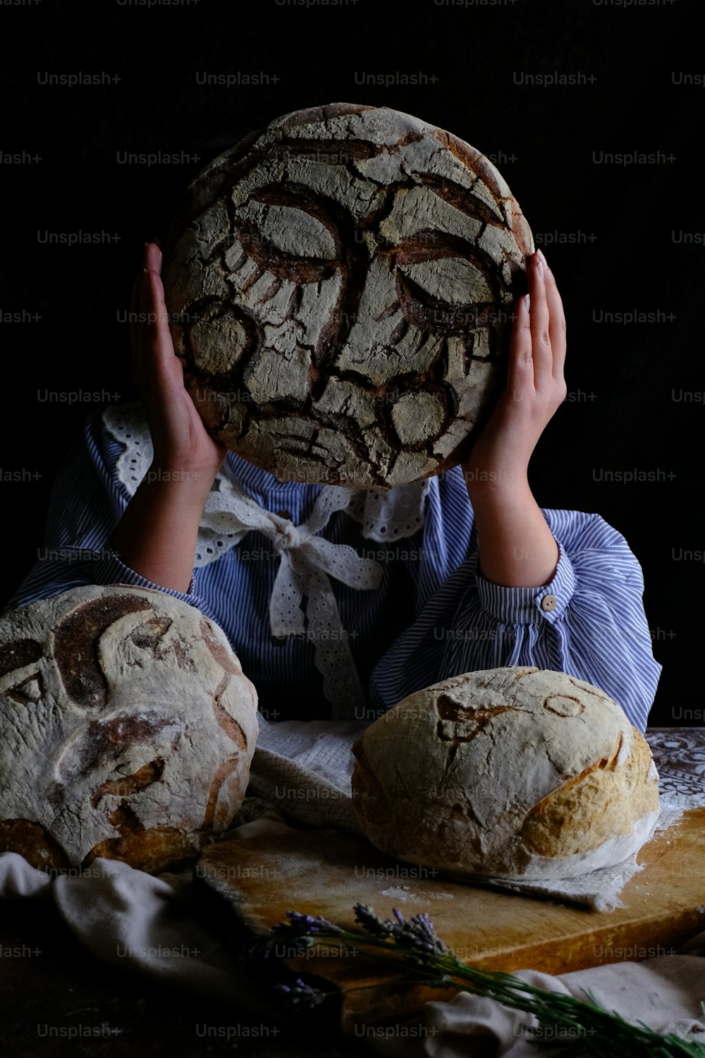 a person holding a loaf of bread over their face